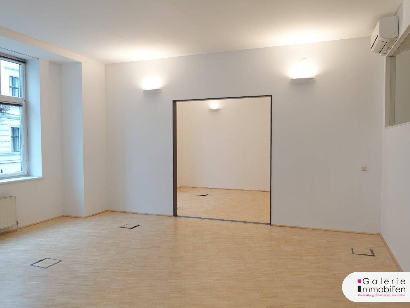Heller Raum mit Holzboden und einer großen Spiegelfläche, die den Raum optisch vergrößert.