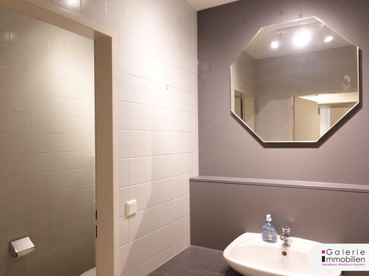 Modernes Gäste-WC mit Waschbecken, Spiegel und hellen Fliesen.