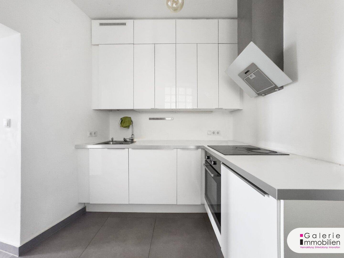 Kompakte, moderne Küche mit weißen Schränken, Induktionskochfeld und Dunstabzugshaube.