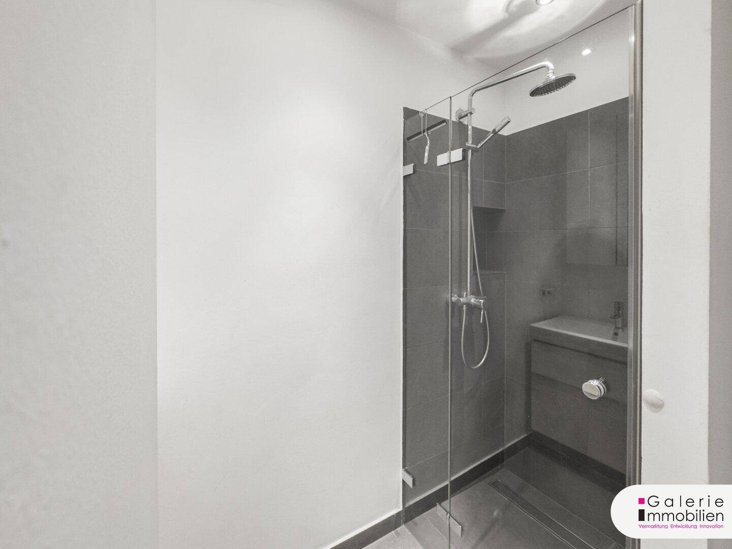 Modernes Badezimmer mit begehbarer Dusche, Regendusche und dunklen Fliesen.