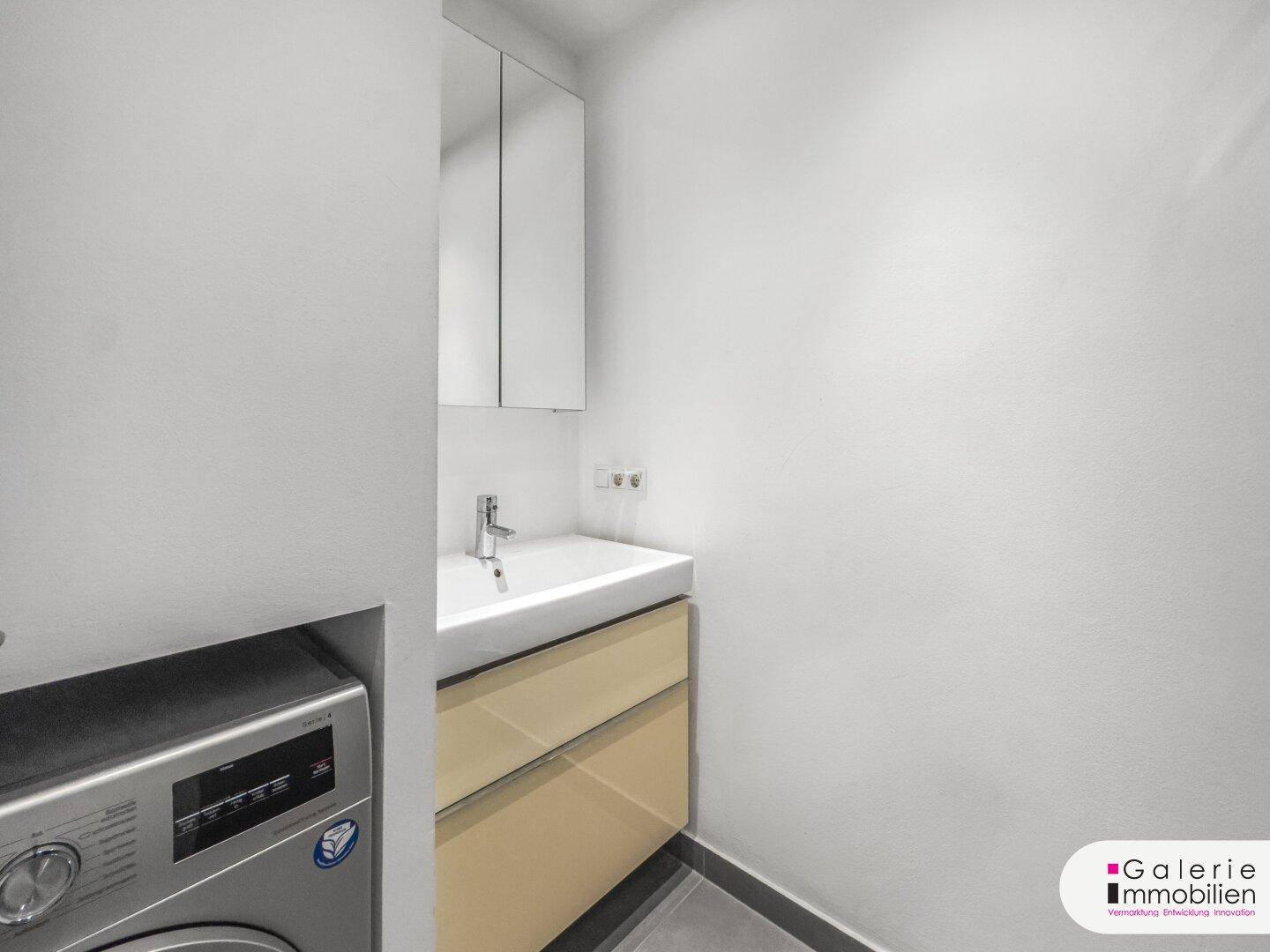 Funktionaler Raum mit Waschmaschine, Waschbecken und Spiegelschrank, ideal als Hauswirtschaftsraum.