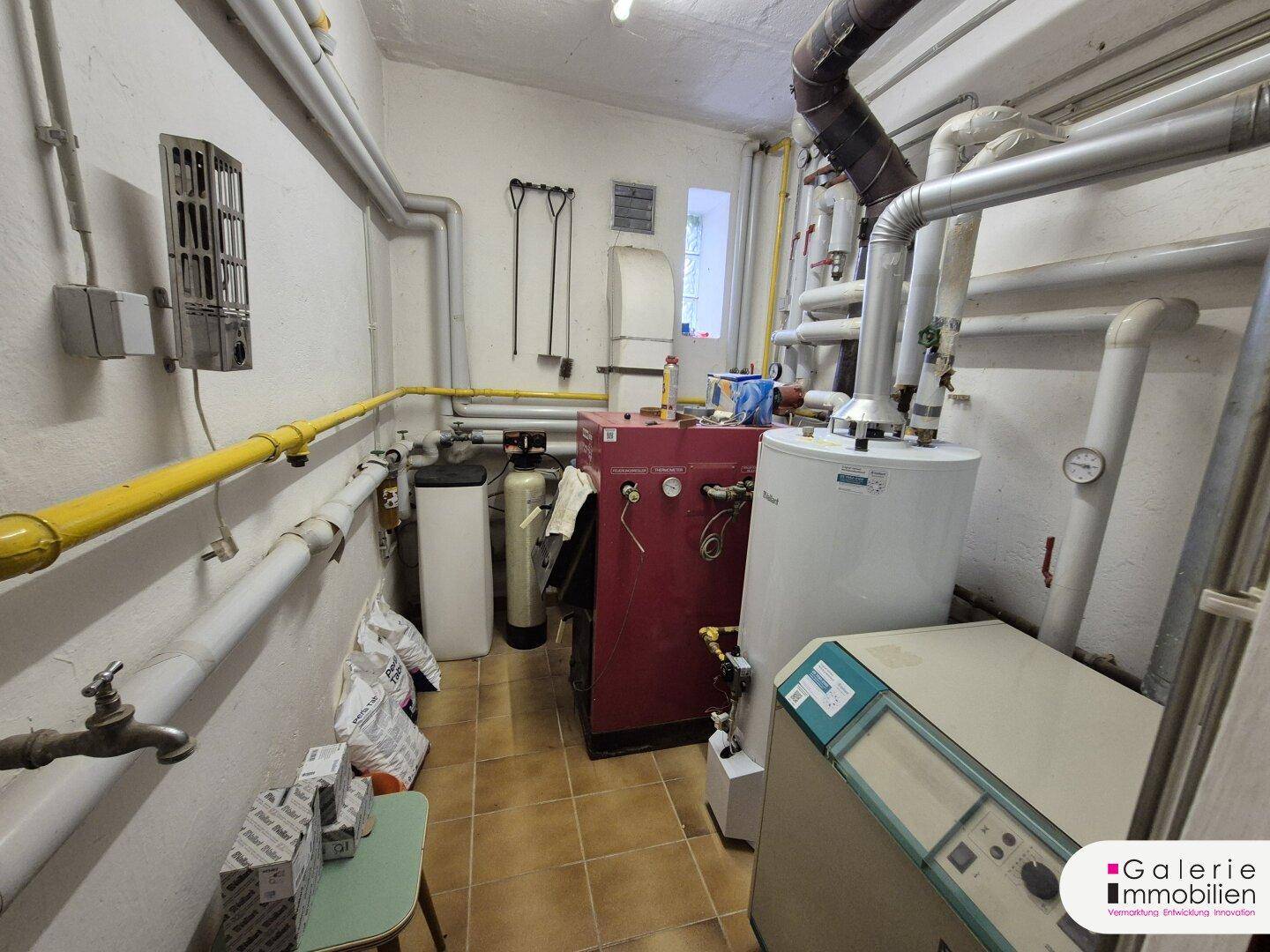 Heizungsraum mit verschiedenen Rohren, Kesseln und technischen Installationen.