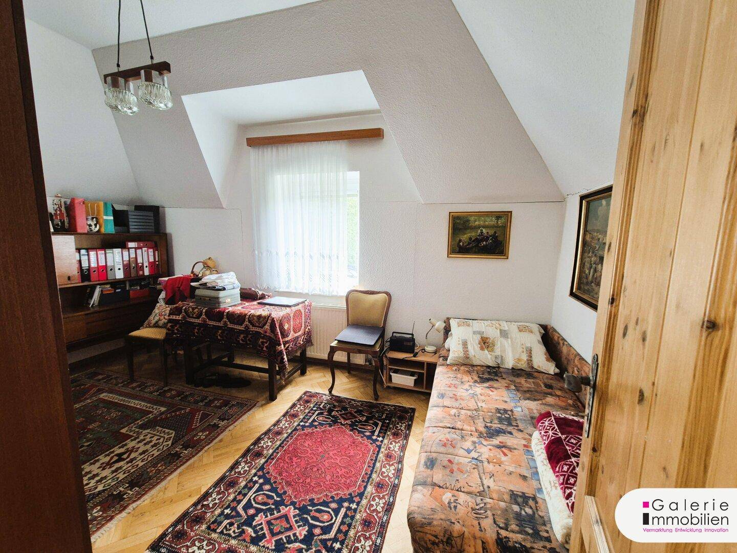 Helles Schlafzimmer mit Dachschrägen, Parkettboden und einem gemütlichen Einzelbett.