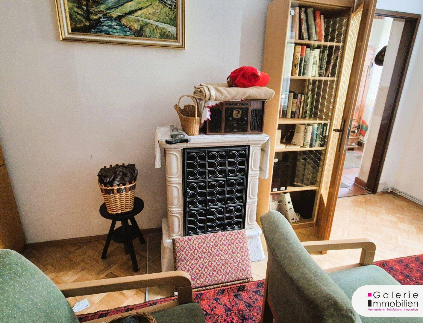 Detailansicht des traditionellen Kachelofens in einem gemütlichen Wohnzimmer mit Teppich.
