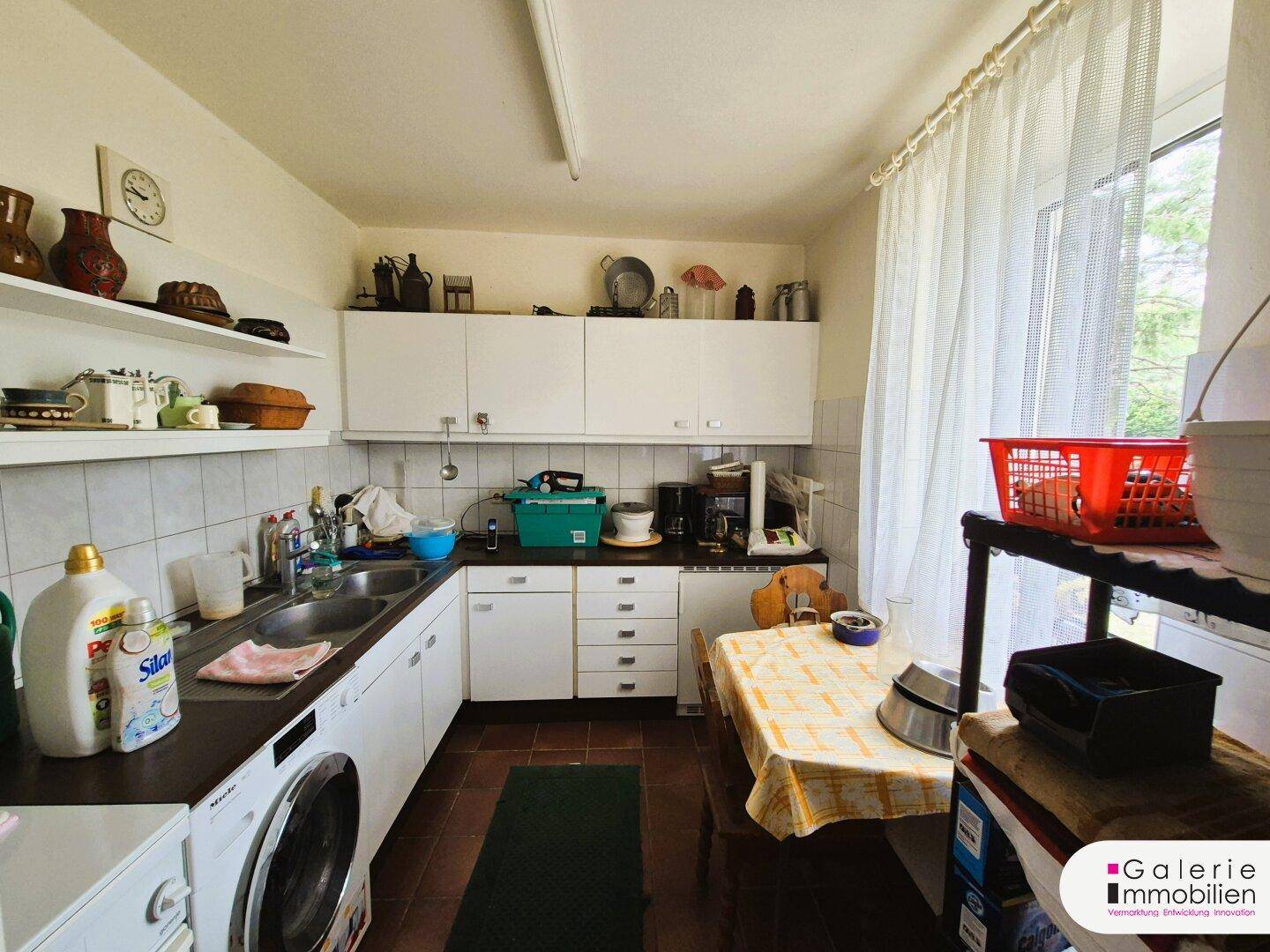 Praktische Küche oder Hauswirtschaftsraum mit Waschmaschine, Spüle und viel Stauraum.