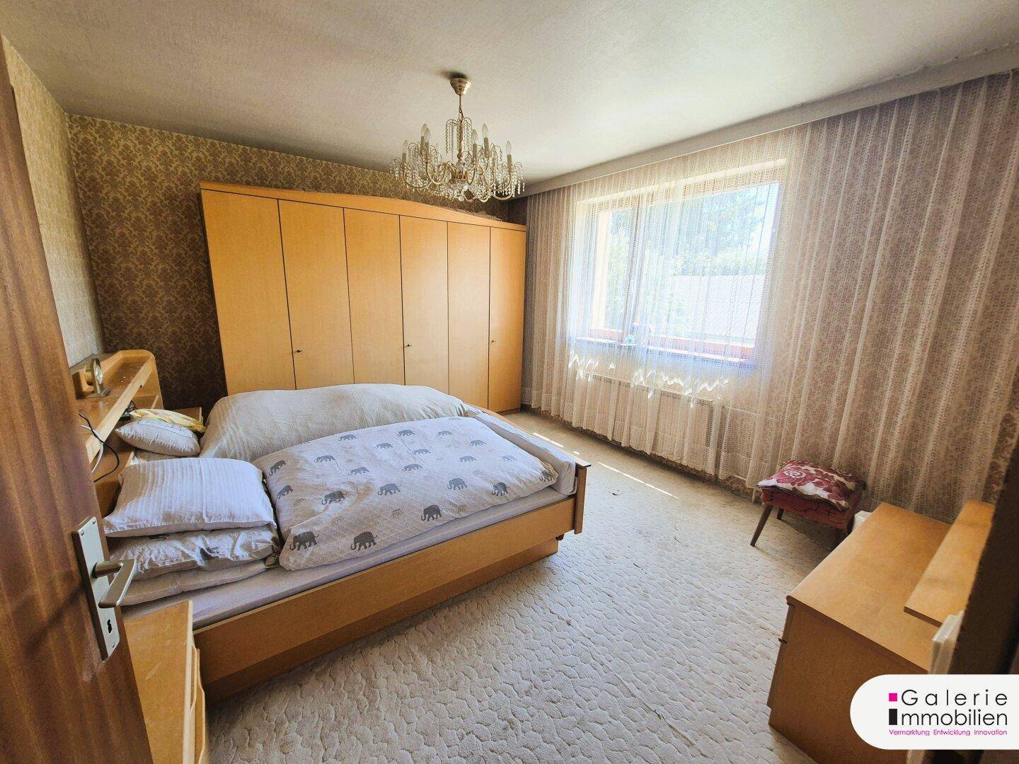 Schlafzimmer mit Doppelbett, großem Kleiderschrank, Teppichboden und viel Tageslicht.