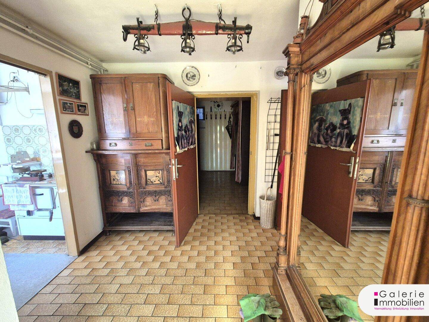 Geräumiger Flur mit Fliesenboden, traditionellen Holzmöbeln und einem großen Spiegel.
