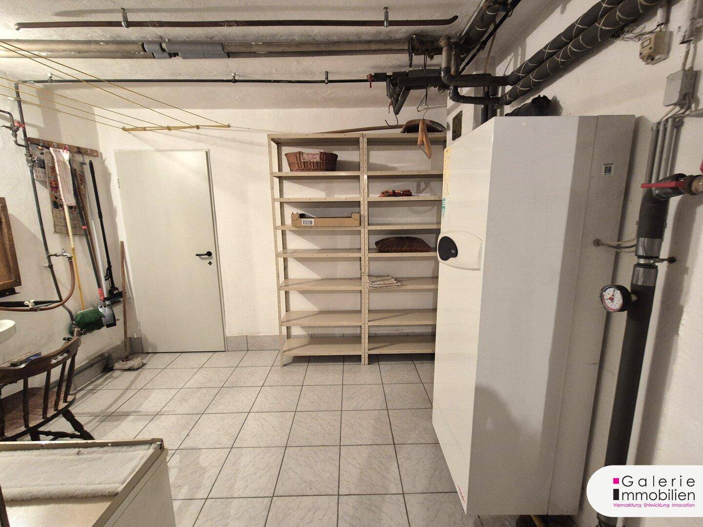 Kellerraum mit Heizungsanlage, Regalen und Fliesenboden, genutzt als Technikraum.