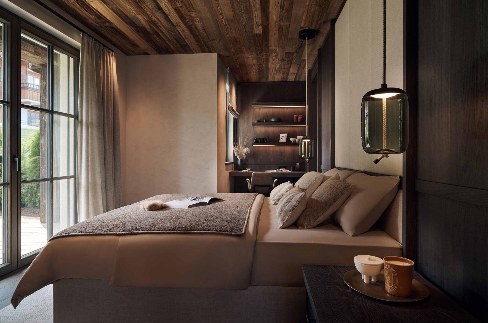 Elegantes Schlafzimmer mit Holzbalkendecke, Schreibtischbereich und Zugang zum Außenbereich.