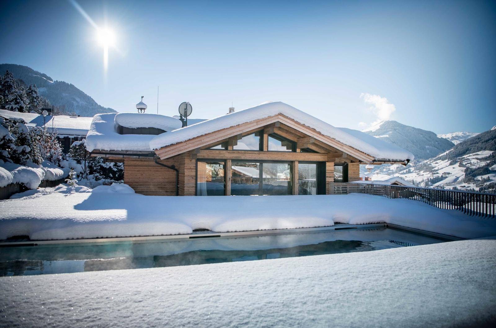 Außenpool in verschneiter Berglandschaft mit Blick auf das moderne Chalet.