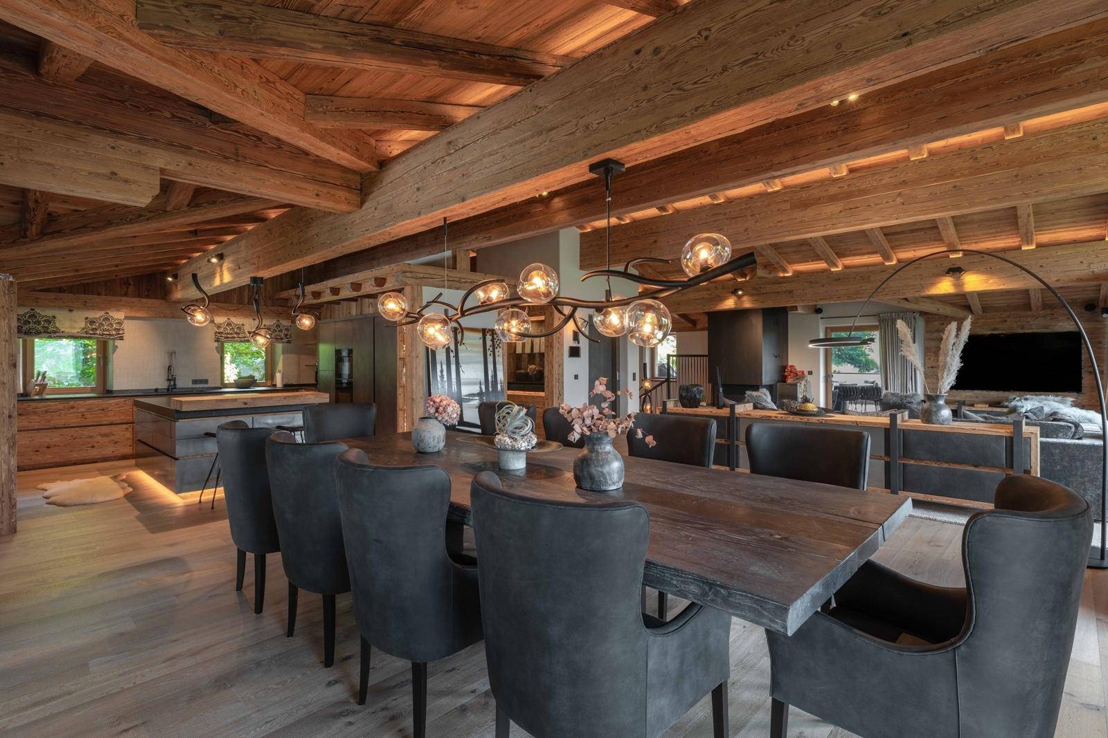 Eleganter Essbereich mit großem Holztisch, modernen Leuchten und Übergang zur Küche.