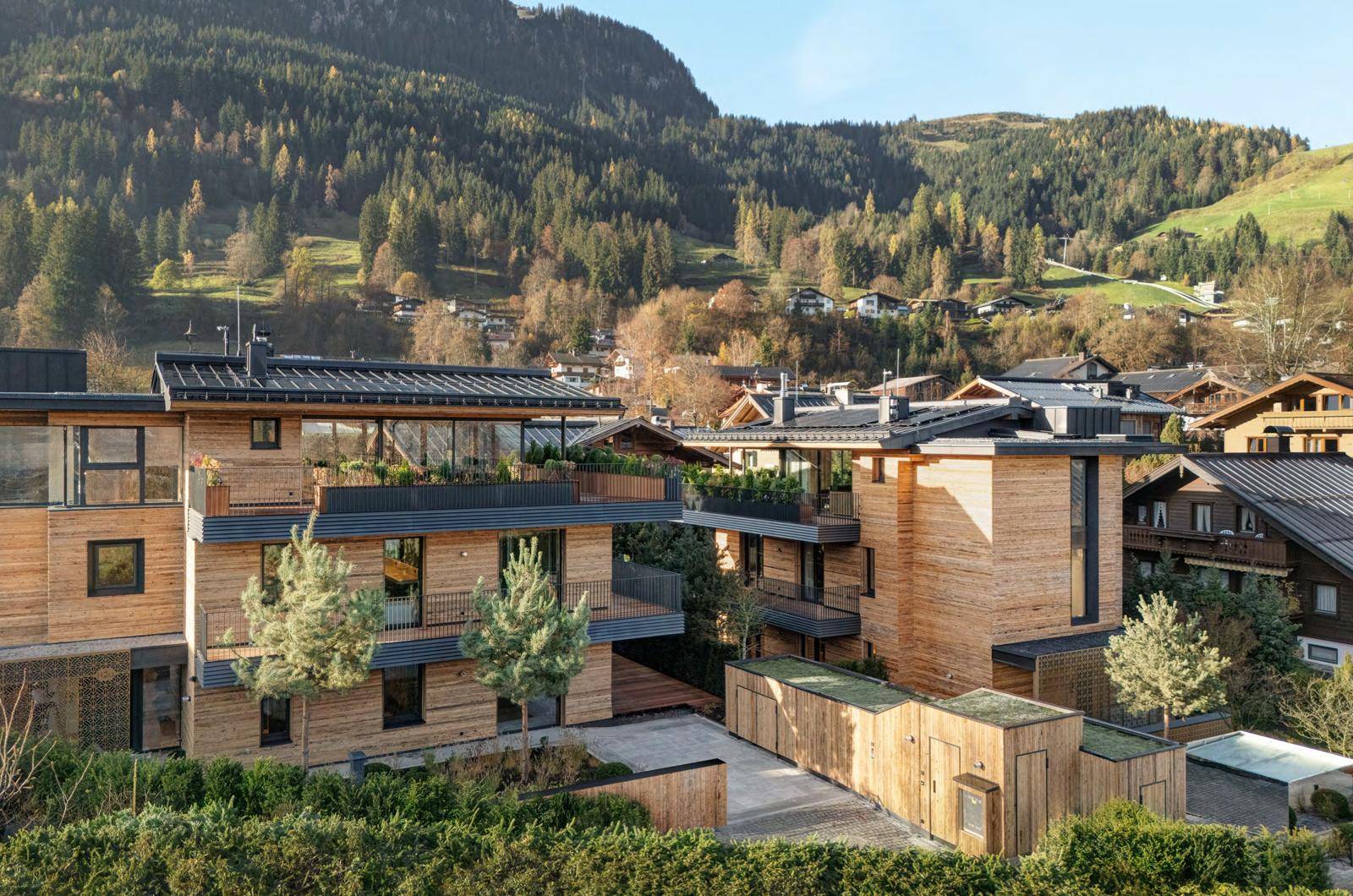 Moderne Wohnanlage mit Holzfassaden, begrünten Dächern und alpiner Umgebung.