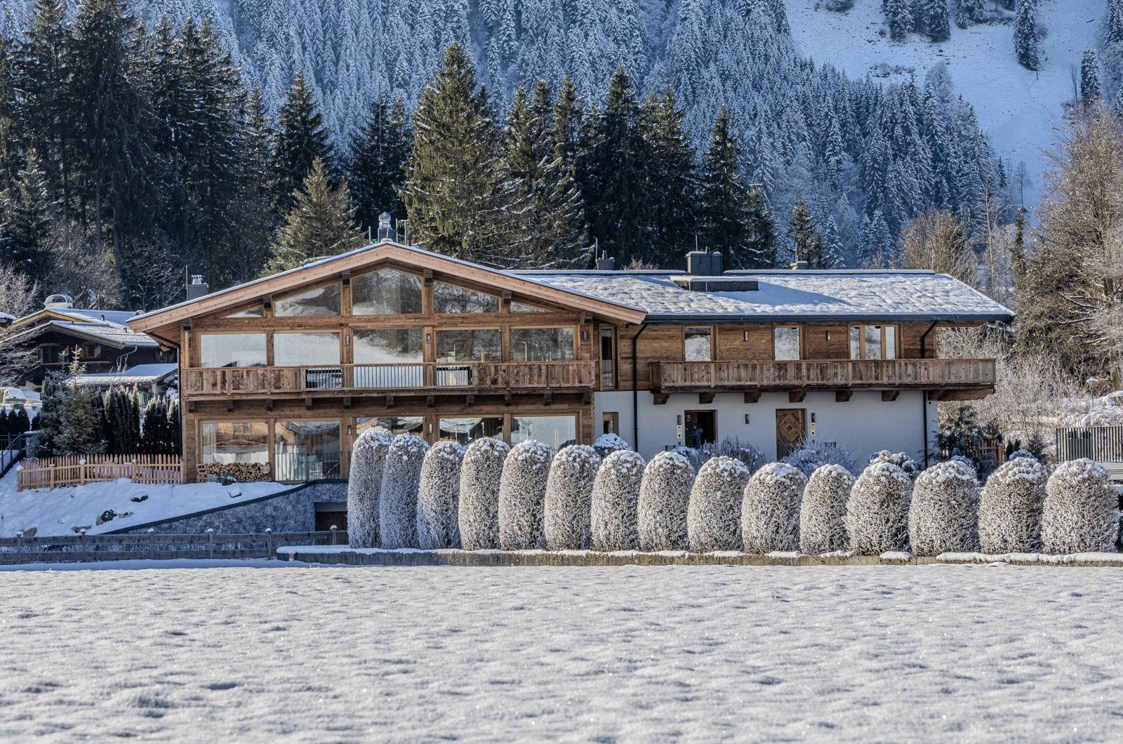 Elegantes Chalet in winterlicher Umgebung mit großen Fenstern und Bergblick.