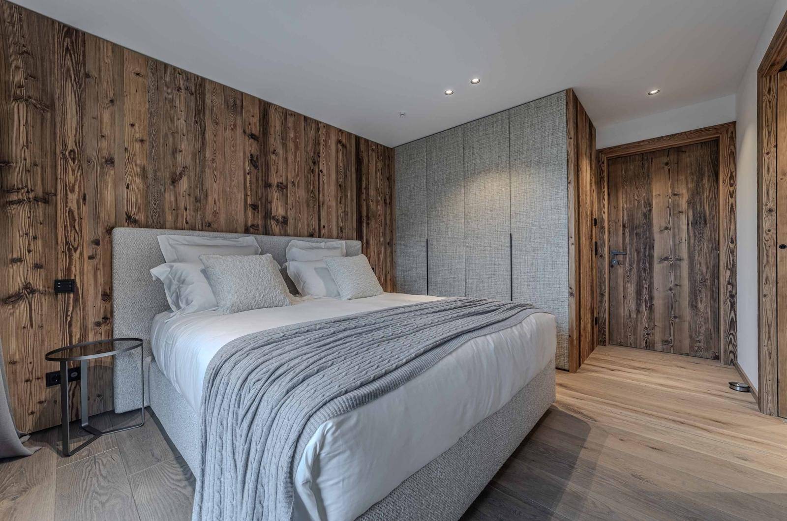 Modernes Schlafzimmer mit Holzwand, Einbauschränken und großem Doppelbett.