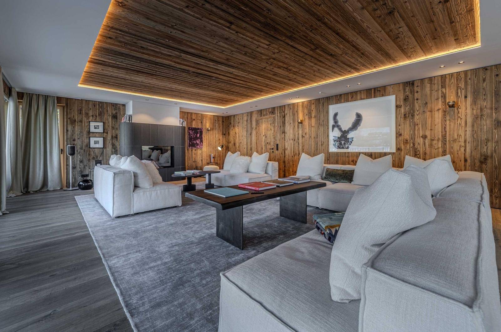 Geräumiges Wohnzimmer mit Holzwänden, Kamin und bequemen Sofas, ideal zum Entspannen.