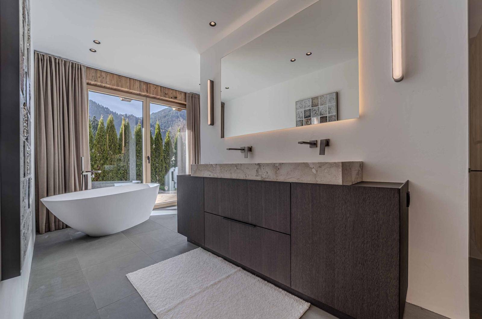 Modernes Badezimmer mit freistehender Badewanne, Doppelwaschbecken und Bergblick.