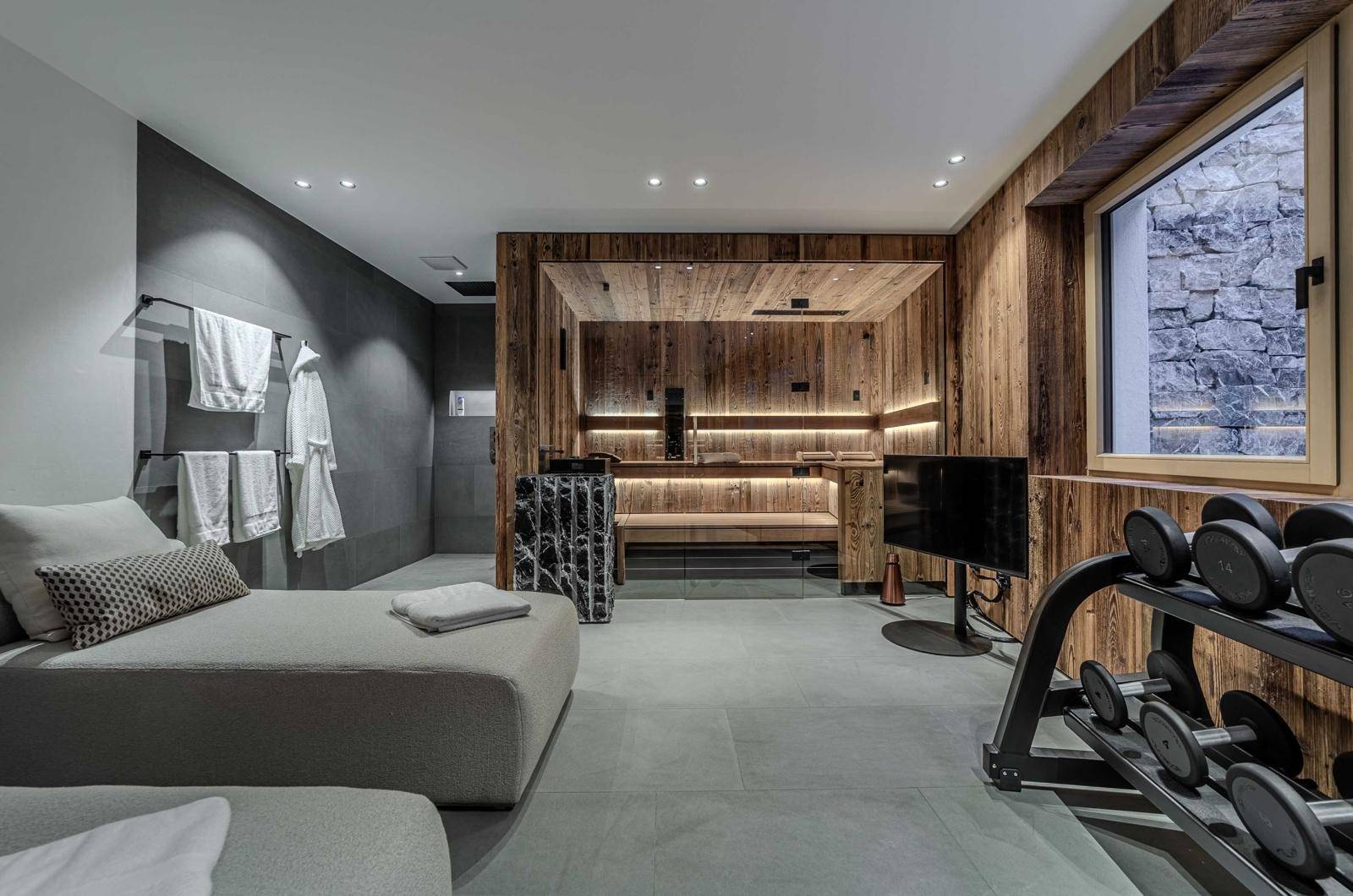 Wellnessbereich mit Sauna, Fitnessgeräten und Liegeflächen für Entspannung.