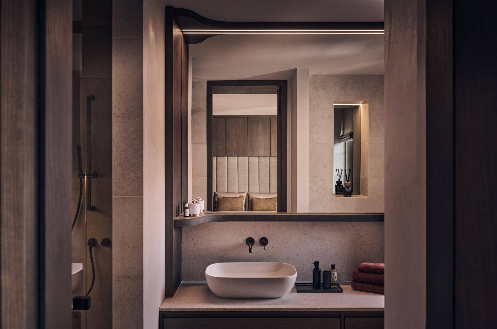 Modernes Badezimmer mit elegantem Waschbecken, Spiegel und indirekter Beleuchtung.