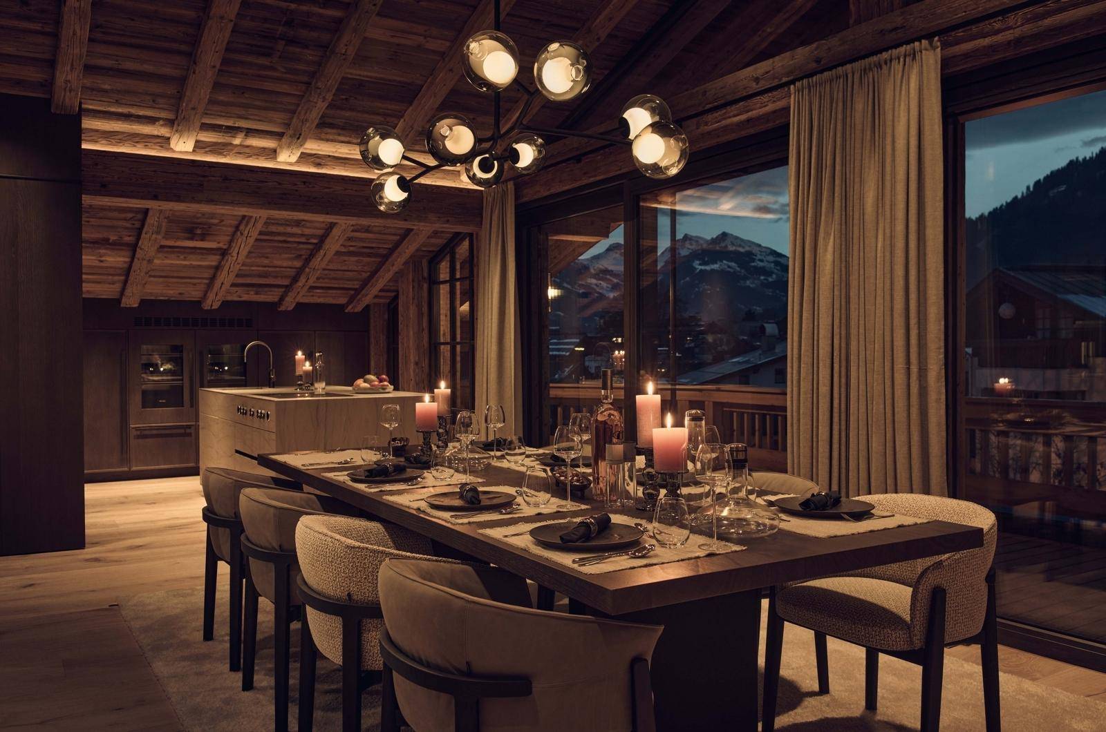 Stilvoller Essbereich mit Holztisch, moderner Beleuchtung und Bergblick bei Abendstimmung.