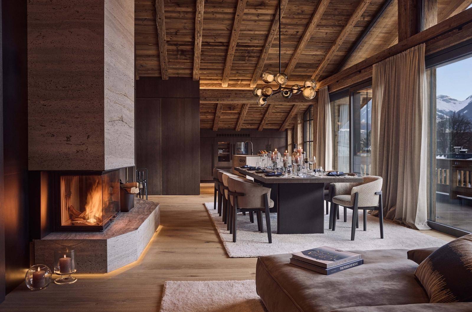 Eleganter Wohn-Essbereich mit Kamin, Holzbalkendecke und Zugang zu einem Balkon mit Bergblick.