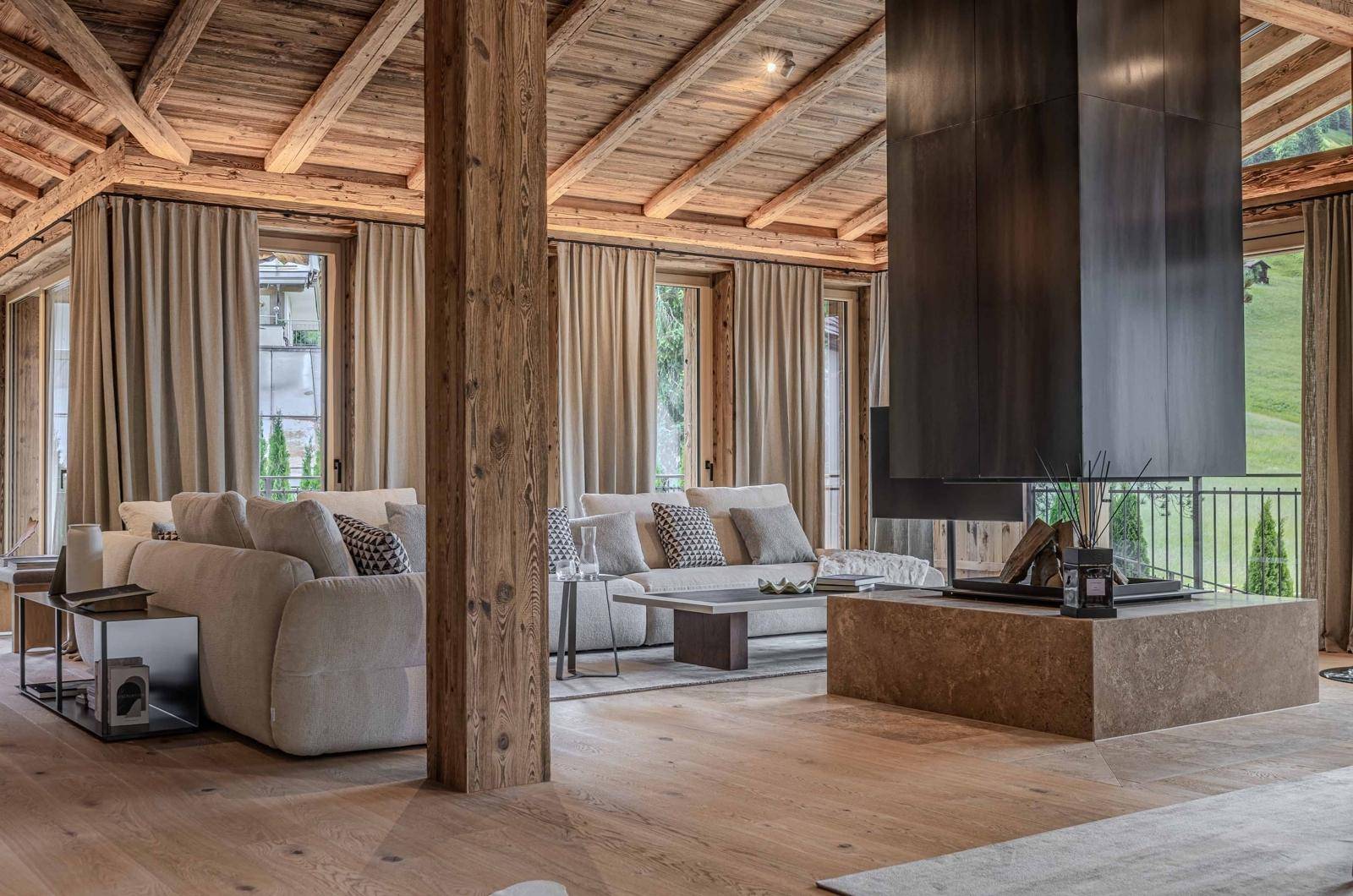 Gemütliches Wohnzimmer im alpinen Stil mit Holzbalkendecke, modernem Kamin und bequemen Sofas.