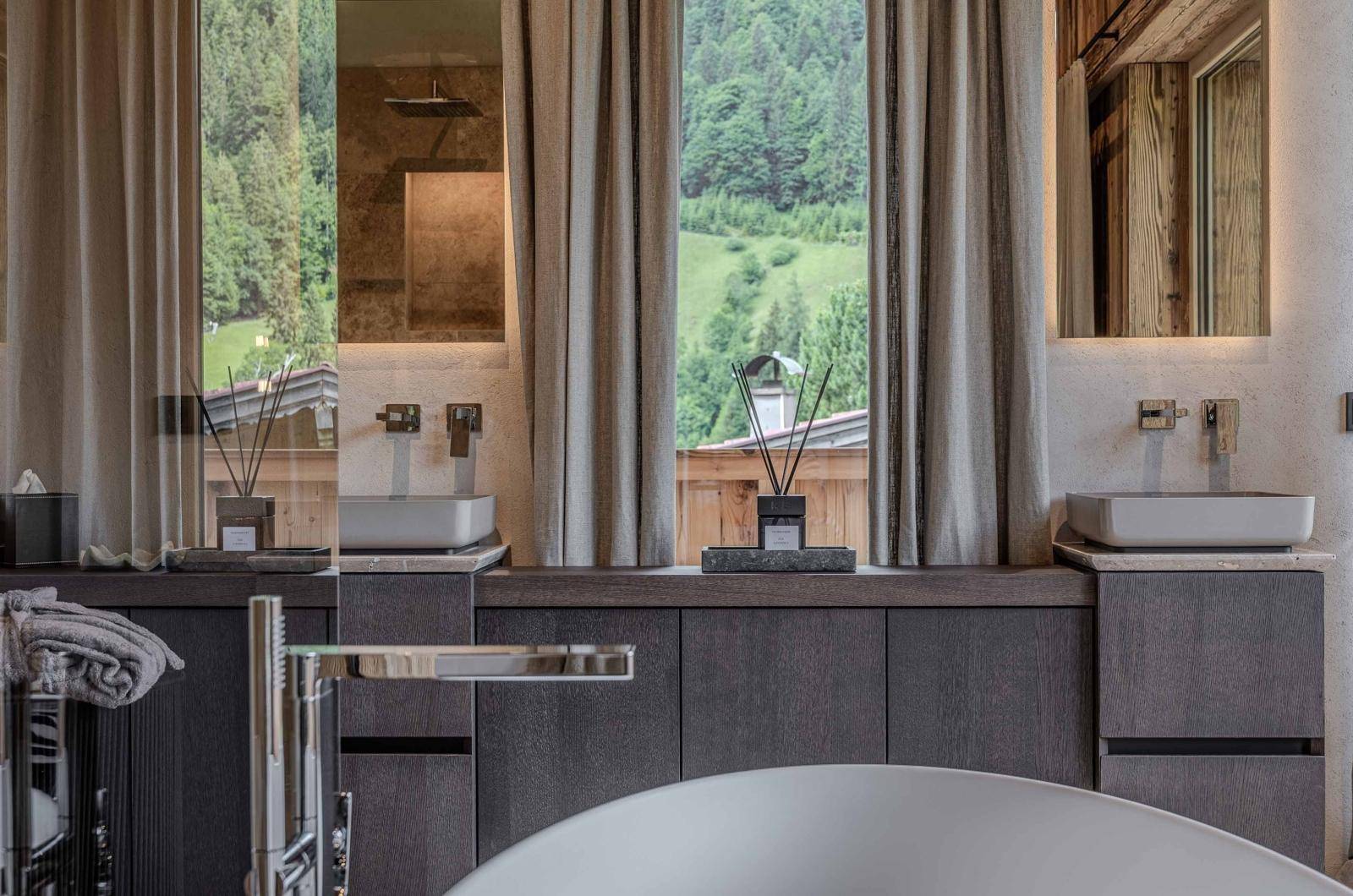 Modernes Badezimmer mit Doppelwaschbecken, freistehender Badewanne und großem Fenster mit Bergblick.