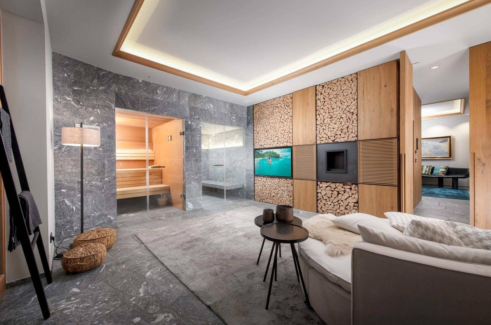 Exklusiver Wellnessbereich mit Sauna, stilvollen Steinwänden und gemütlicher Sitzecke zum Entspannen.