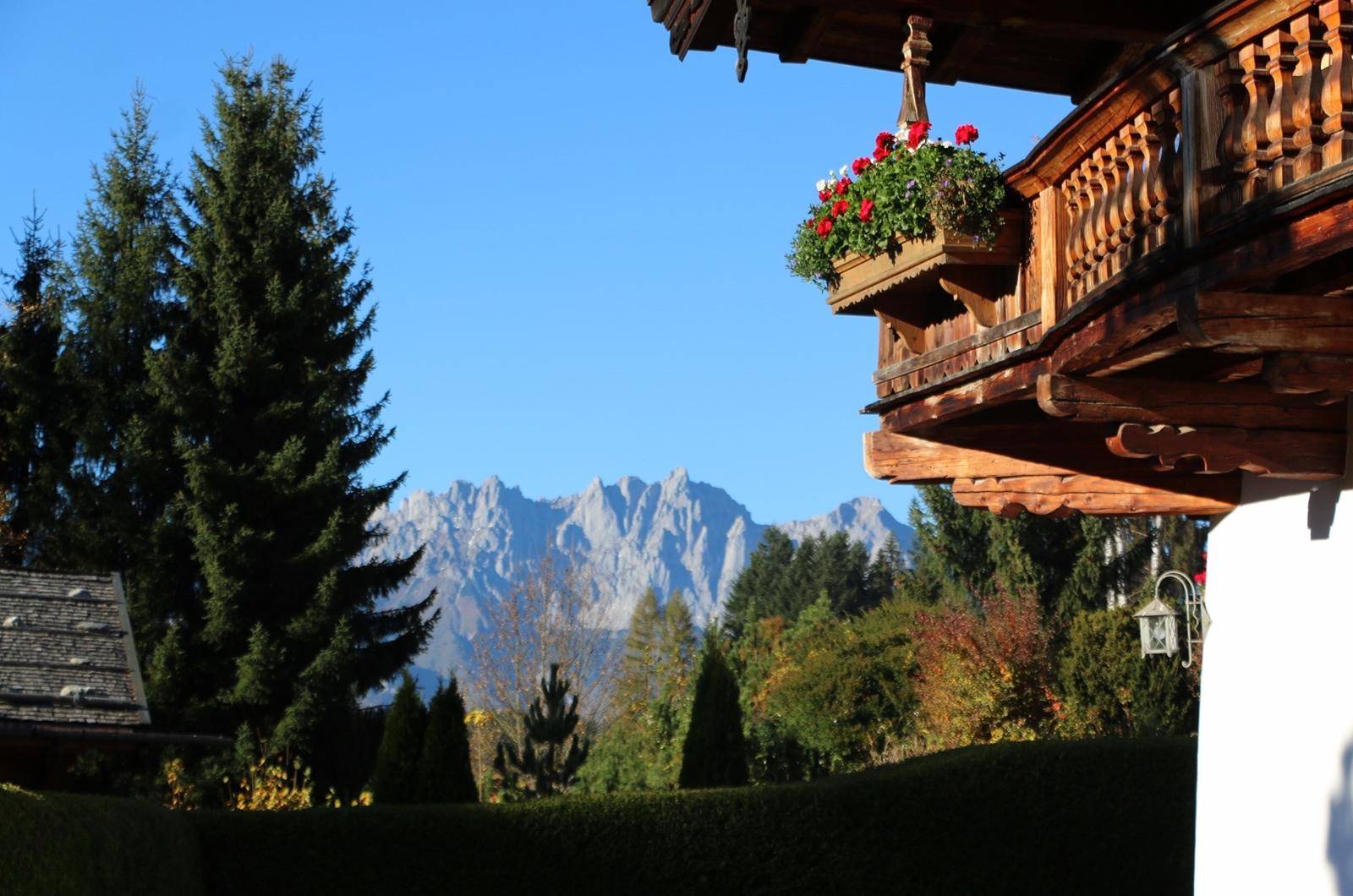 Traditioneller Holzbalkon mit Blumenkästen und atemberaubendem Bergblick in die Ferne.