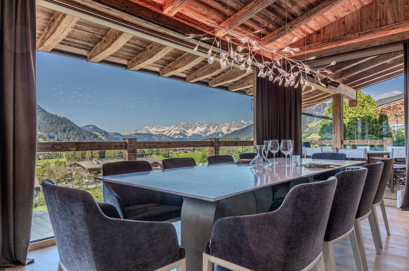Eleganter Essbereich mit Holzbalkendecke und Panoramafenstern, die einen spektakulären Bergblick bieten.