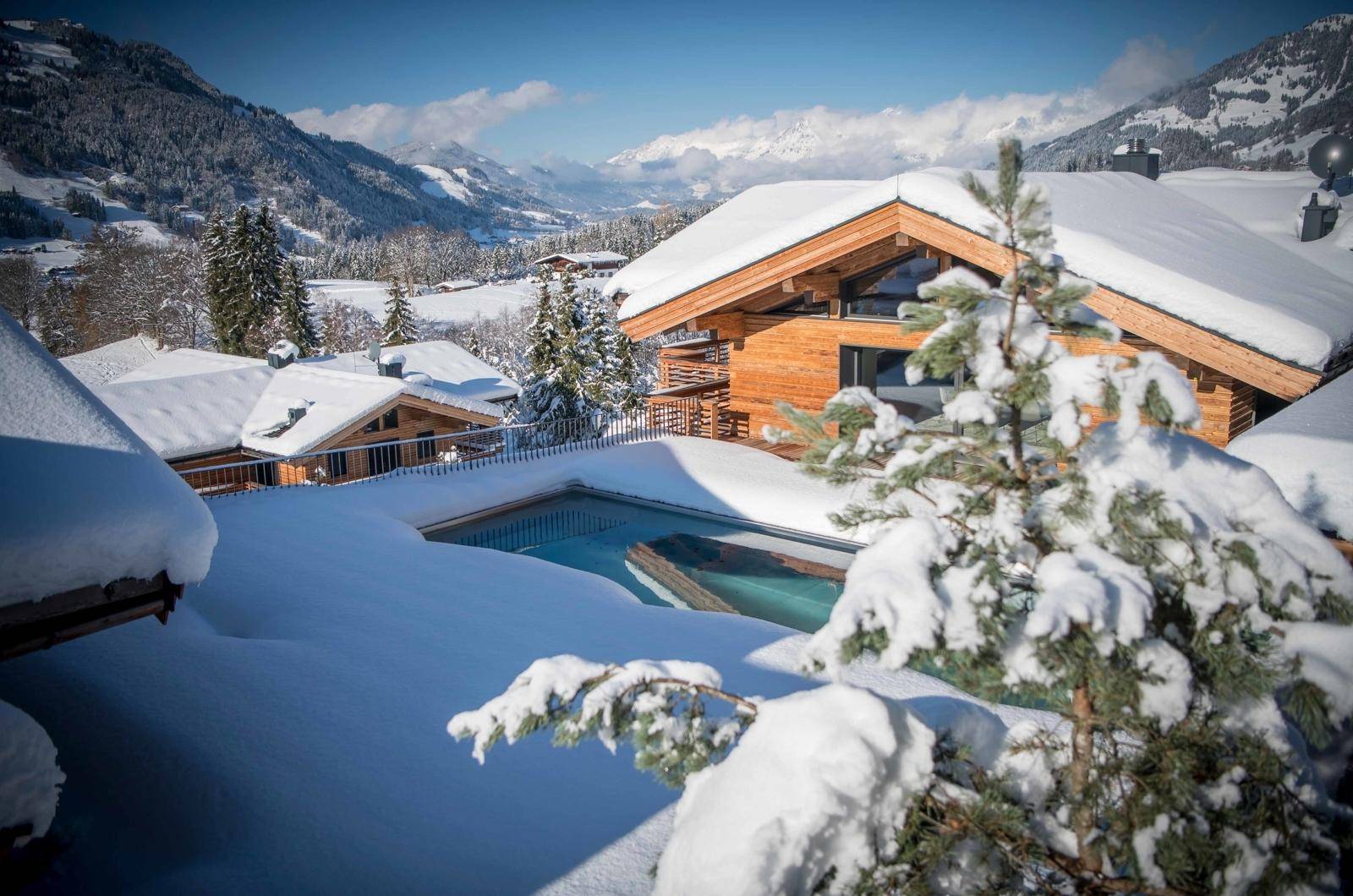 Außenpool in verschneiter Berglandschaft mit Blick auf das luxuriöse Chalet.