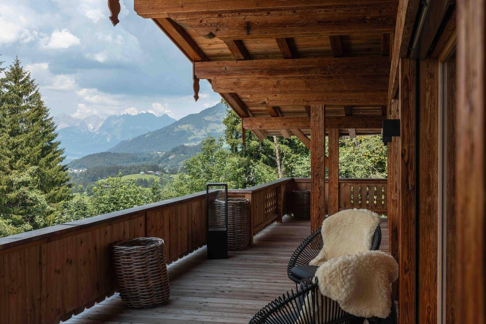Geräumiger Holzbalkon mit Sitzgelegenheiten und atemberaubendem Bergblick über die Alpen.
