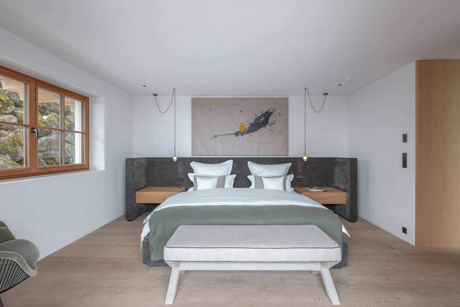Modernes Schlafzimmer mit großem Bett, Holzboden und Fenster mit Blick auf die Natur.
