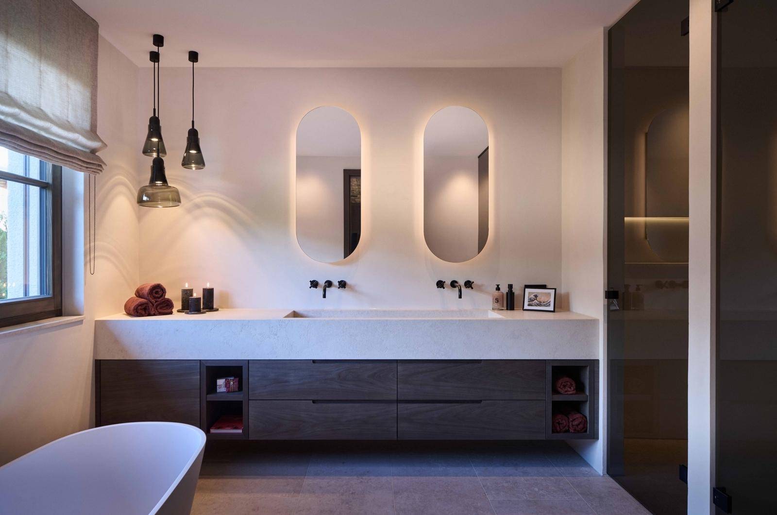 Modernes Badezimmer mit Doppelwaschbecken, freistehender Badewanne und indirekter Beleuchtung.