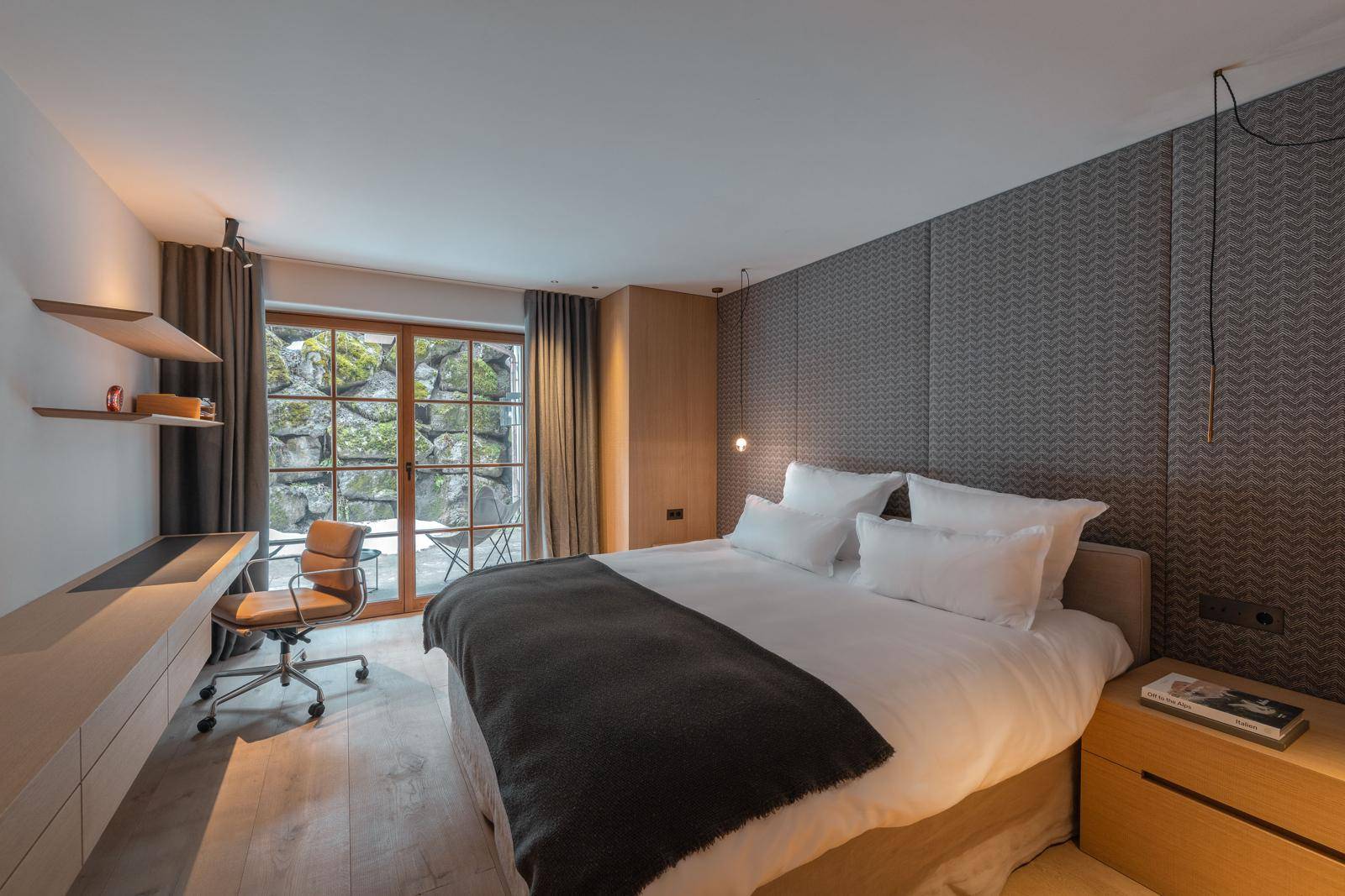 Gemütliches Schlafzimmer mit Schreibtisch, Holzboden und Zugang zu einem kleinen Außenbereich.