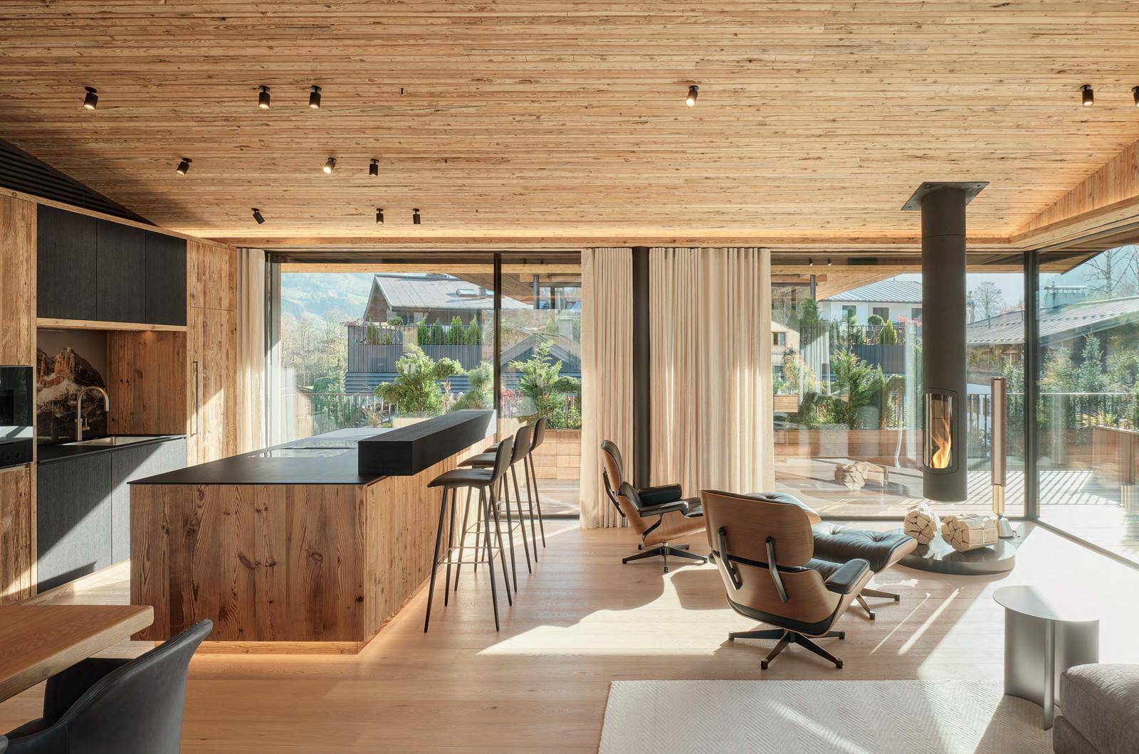 Offener Wohnbereich mit Holzküche, Essbereich und gemütlicher Sitzecke am Kamin.