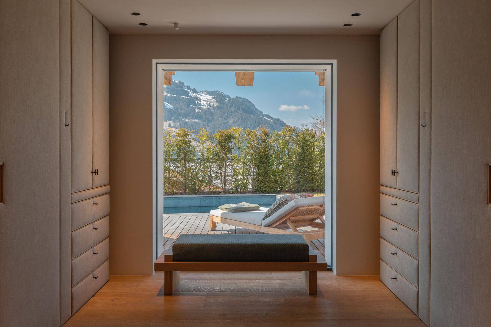Geräumiger begehbarer Kleiderschrank mit Einbauschränken und Blick auf den Poolbereich.