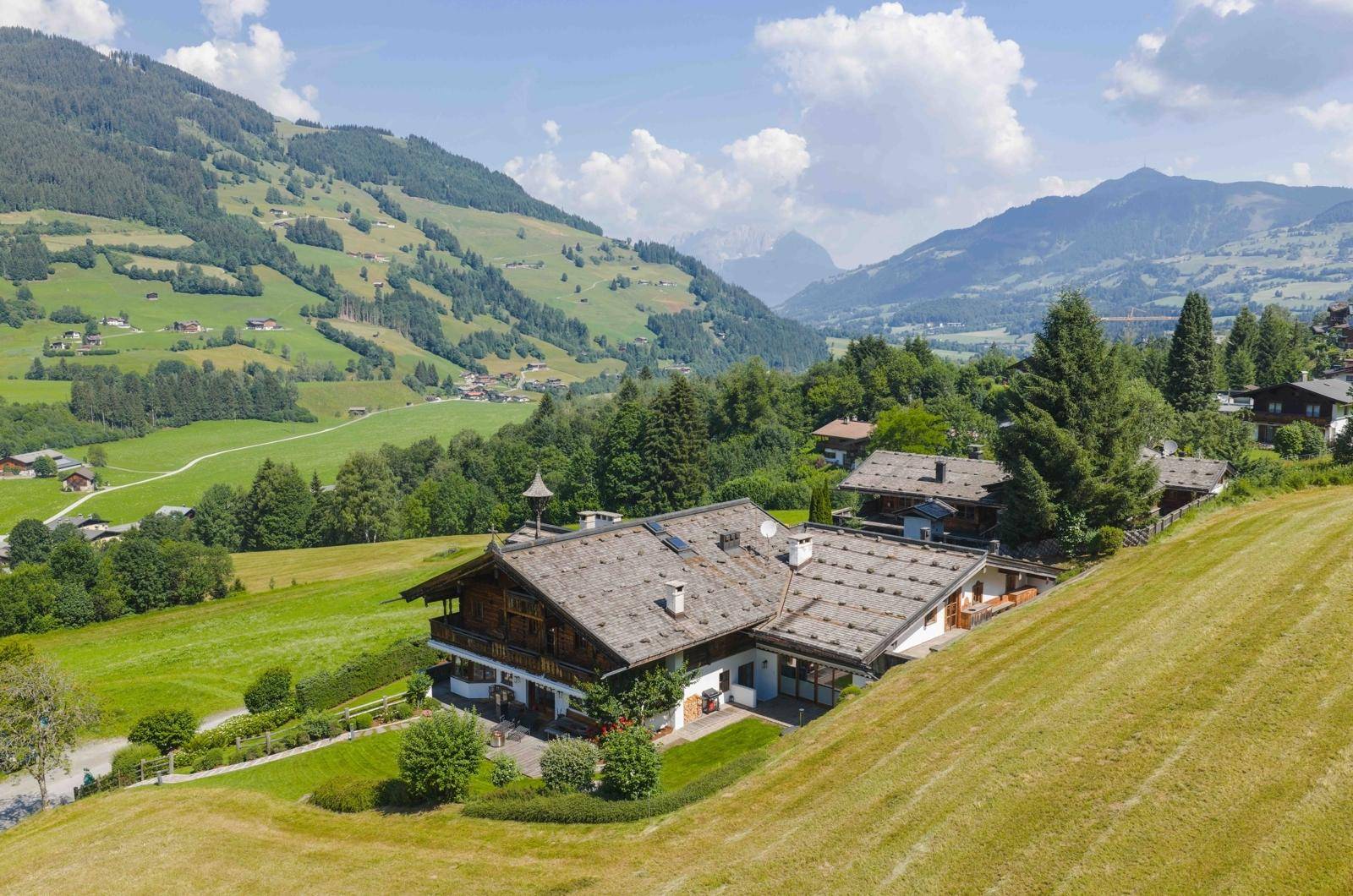 Panoramablick auf das Anwesen in den Alpen, umgeben von grünen Hängen und majestätischen Bergen.