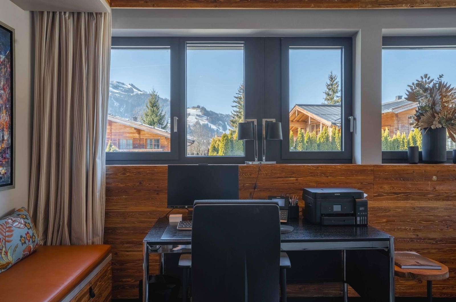 Arbeitszimmer mit Holzvertäfelung, großem Fenster und Blick auf die umliegende Berglandschaft.