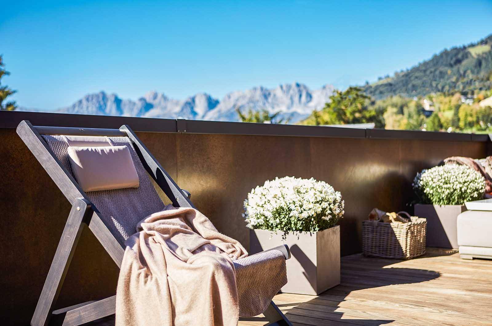 Entspannungsbereich auf der Terrasse mit Liegestuhl und weitem Blick auf die majestätischen Berge.