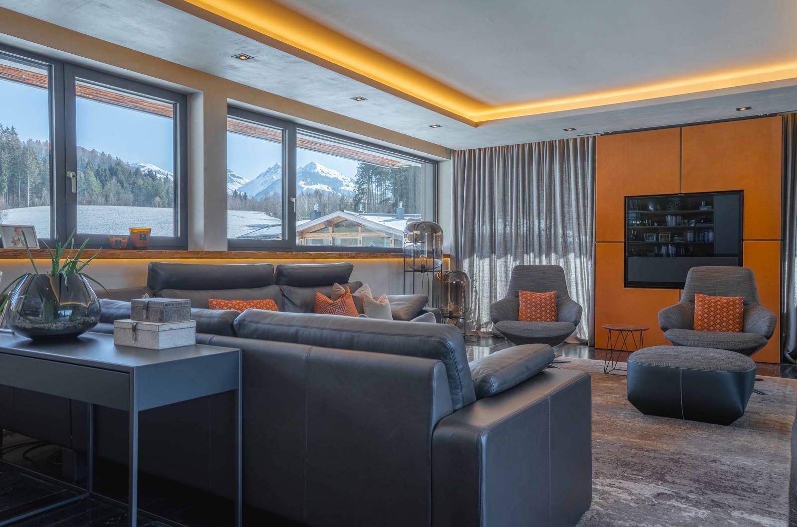 Gemütliches Wohnzimmer mit bequemen Sofas, modernen Sesseln und Blick auf die verschneite Berglandschaft.