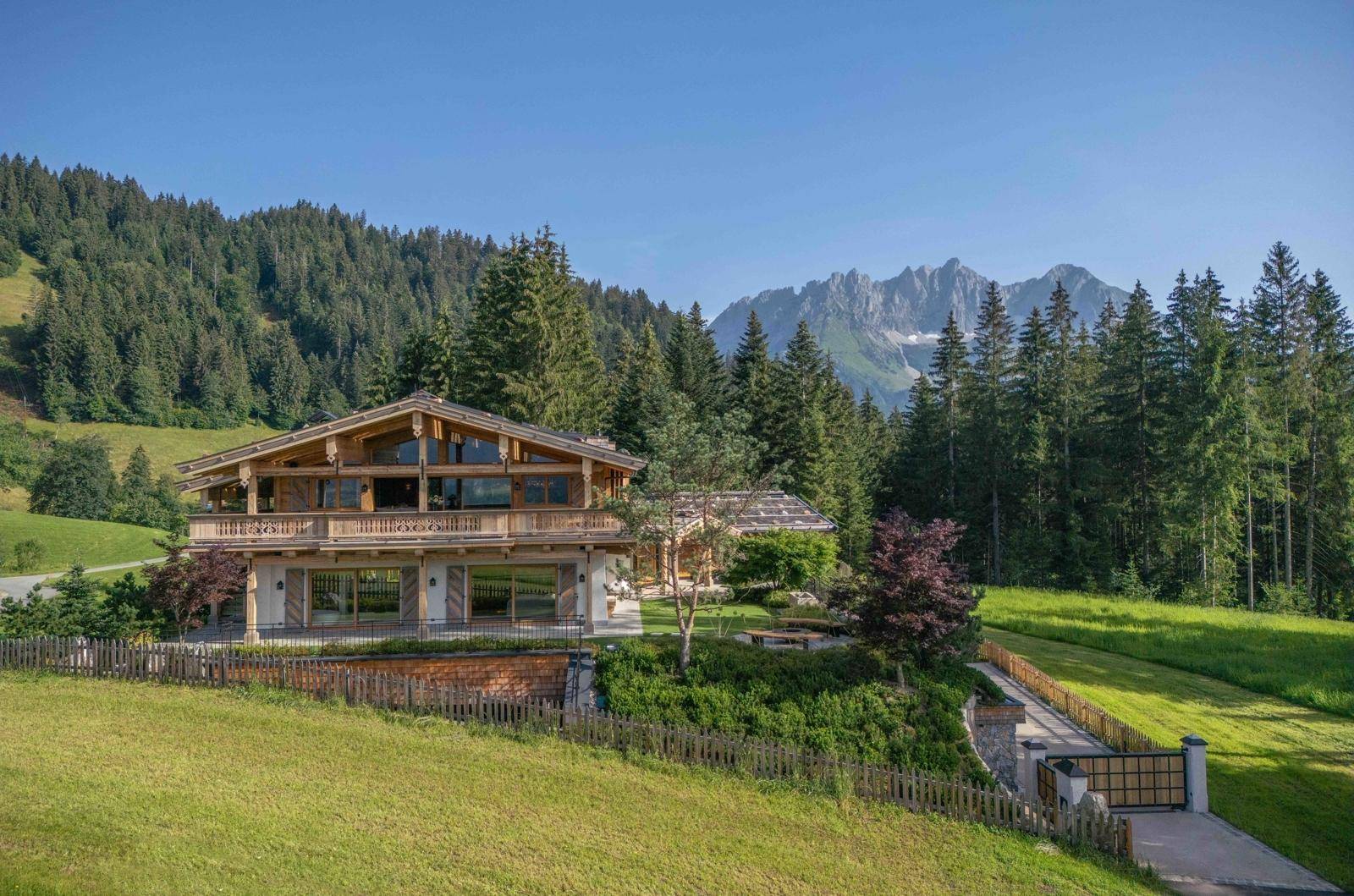 Großzügiges Chalet in alpiner Landschaft mit beeindruckendem Bergblick und weitläufigen Grünflächen.