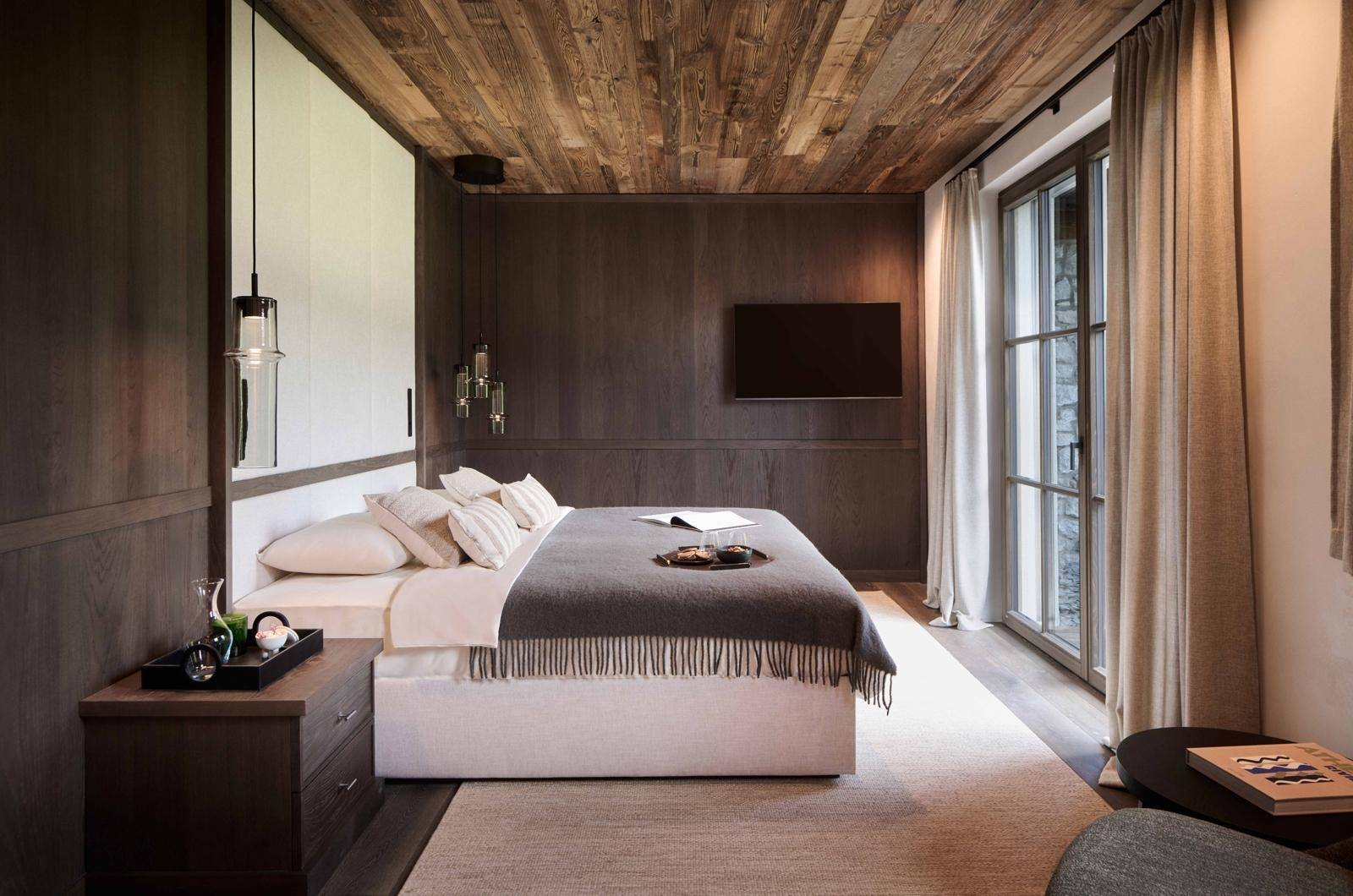 Stilvolles Schlafzimmer mit Holzbalkendecke, großem Bett und direktem Zugang zum Balkon.