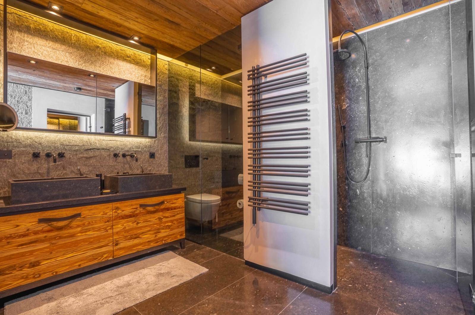 Modernes Badezimmer mit Doppelwaschbecken, begehbarer Dusche und beheiztem Handtuchhalter.