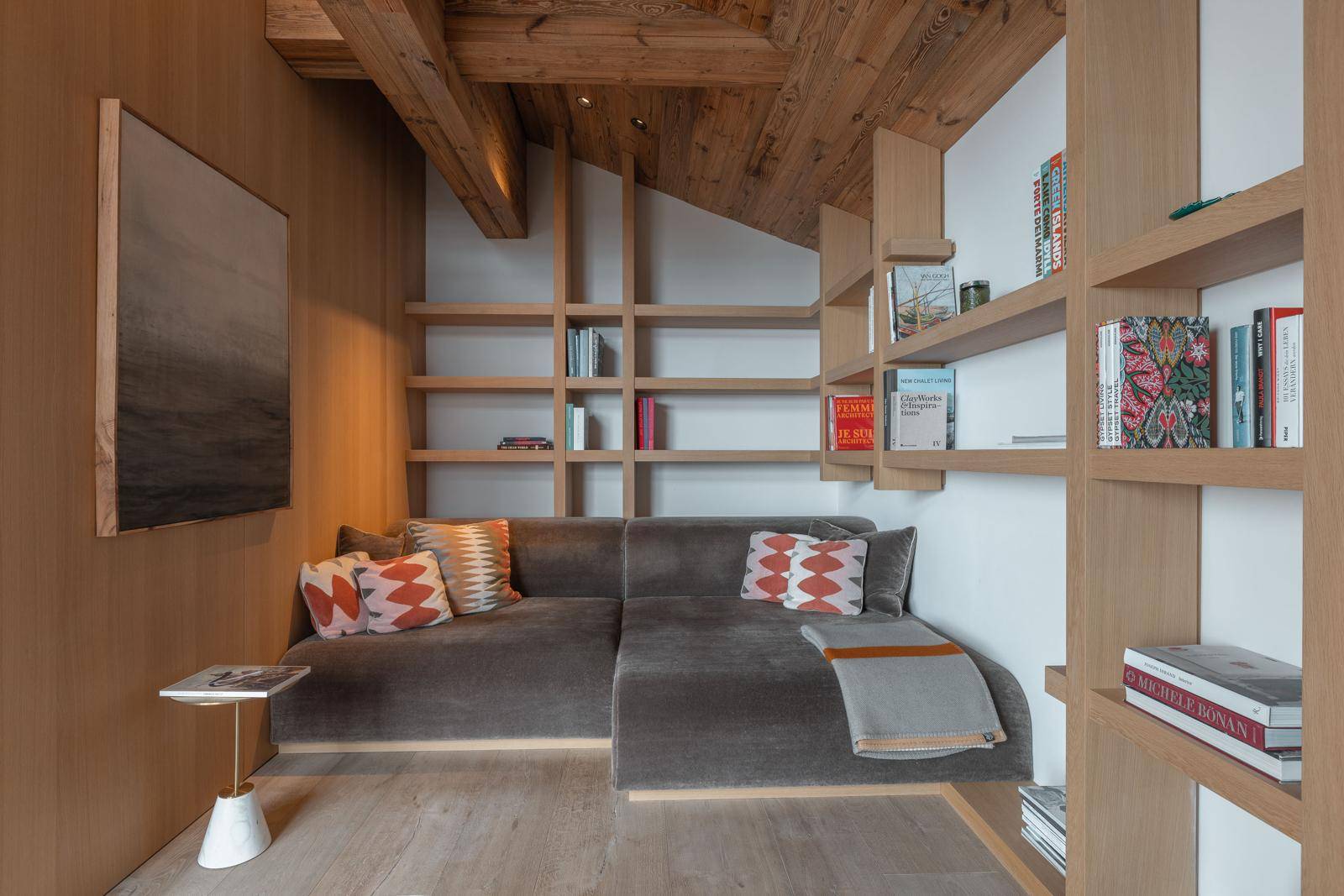 Gemütliche Leseecke mit eingebauten Regalen, bequemer Couch und Holzwänden.
