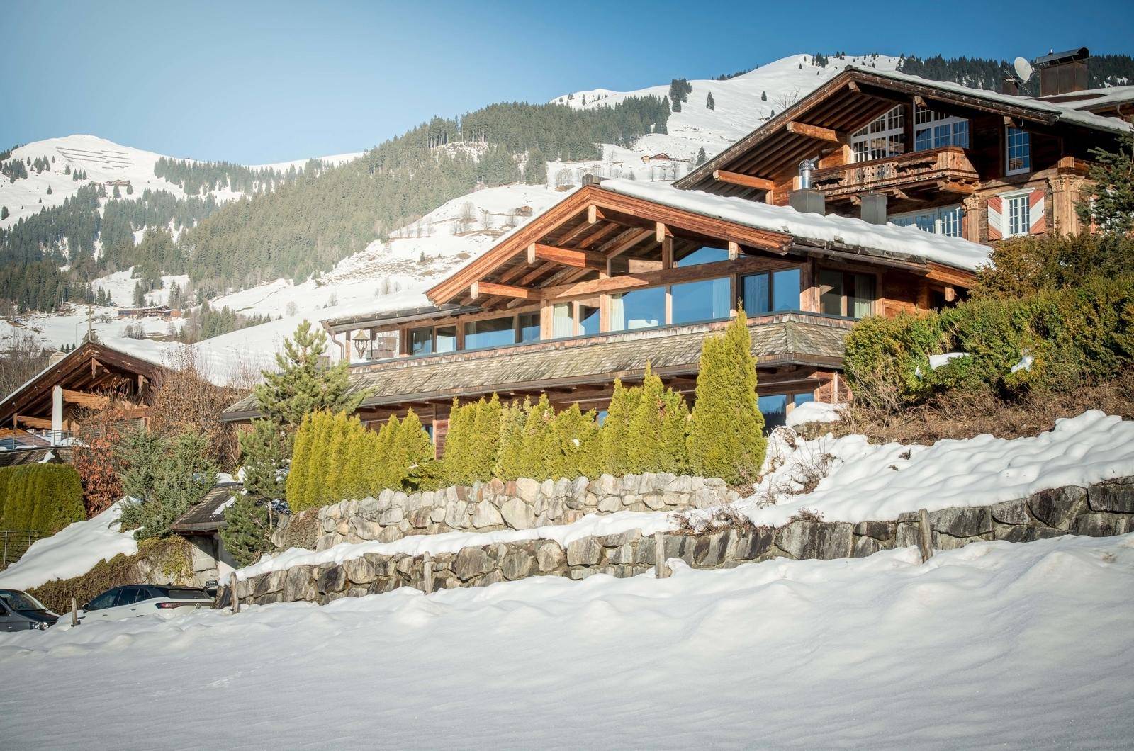 Luxuriöses Holzchalet in verschneiter Winterlandschaft mit majestätischem Bergblick.