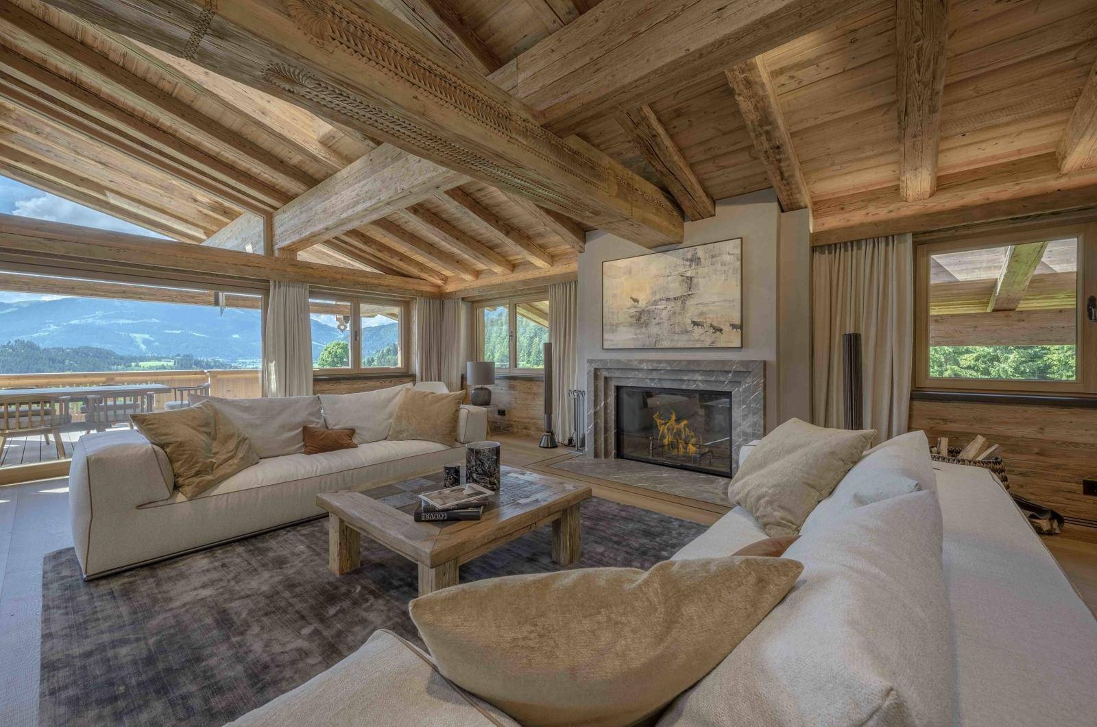 Gemütliches Wohnzimmer mit Kamin, bequemen Sofas und atemberaubendem Bergblick.