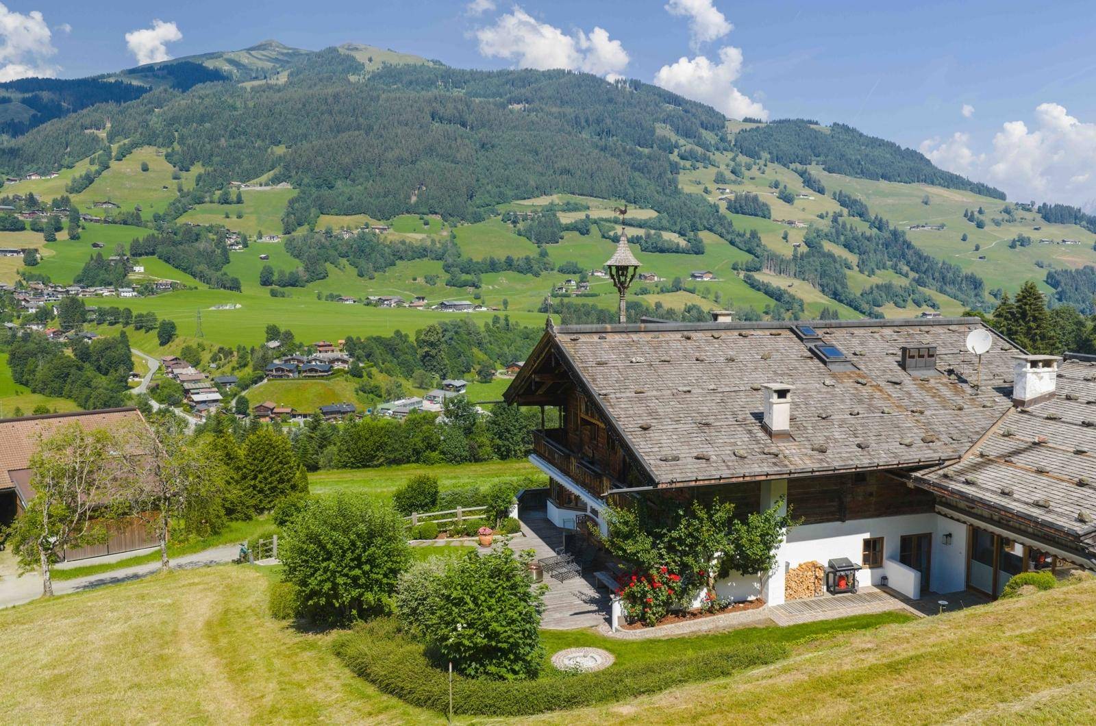 Alpines Anwesen mit traditioneller Architektur, umgeben von grünen Wiesen und Bergen.