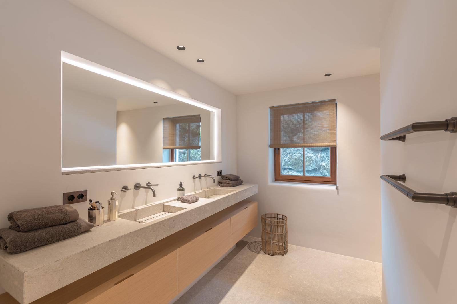 Modernes Badezimmer mit Doppelwaschbecken, beleuchtetem Spiegel und Fenster.