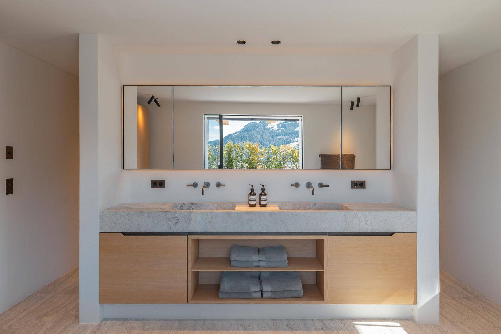 Elegantes Badezimmer mit Doppelwaschbecken, großem Spiegel und Bergblick durch das Fenster.