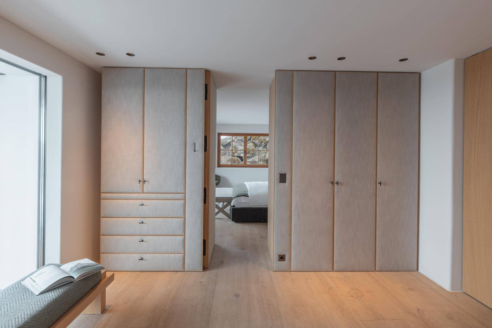 Heller begehbarer Kleiderschrank mit maßgefertigten Schränken und Zugang zum Schlafzimmer.